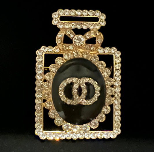 Gold and black jeweled perfume brooch.