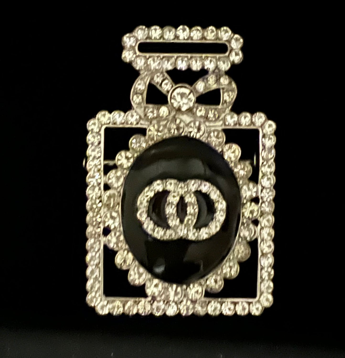 Silver and black jeweled perfume brooch.