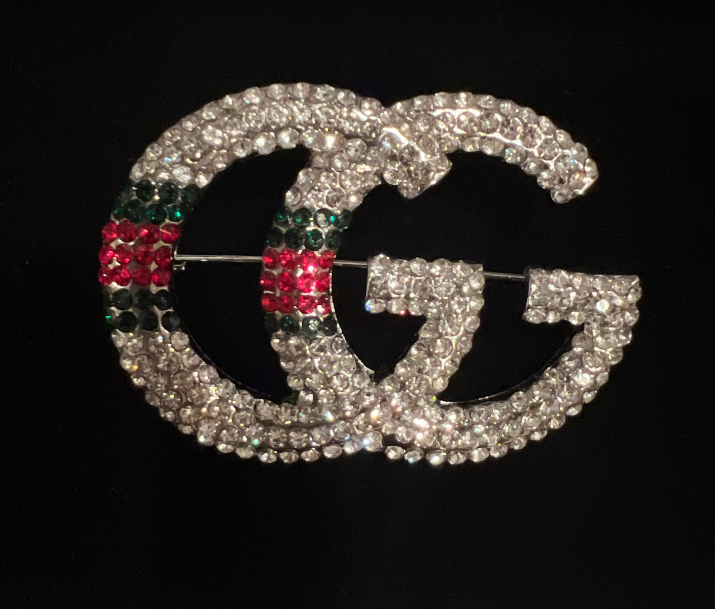 Casting brooch with G rhinestones in silver, red and green.